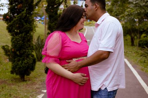 Marido beijando a testa da esposa durante um ensaio de gestante'