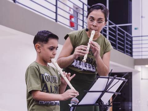 Professora tocando flauta junto com seu aluno'