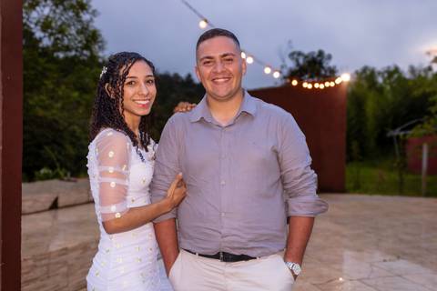 Casal posando para foto com luzes ao fundo'