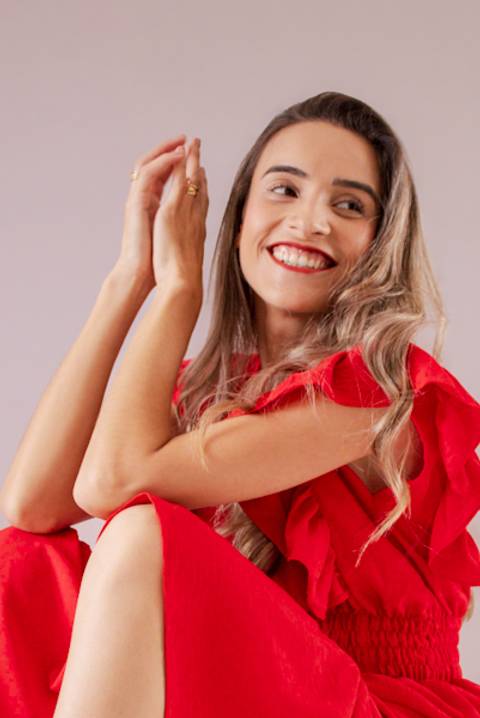 mulher de vestido vermelho sorrindo para foto. Foto de Mary Santtiago'