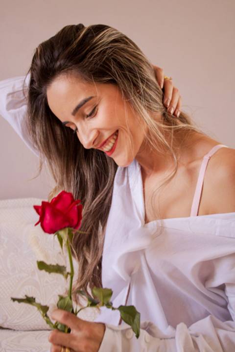 mulher de roupa branca segurando uma rosa vermelha. Foto de Mary Santtiago'