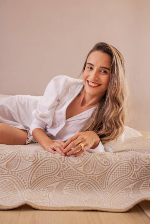 Mulher de roupa branca deitada na cama posando para foto em seu ensaio de aniversário. Foto de Mary Santtiago'