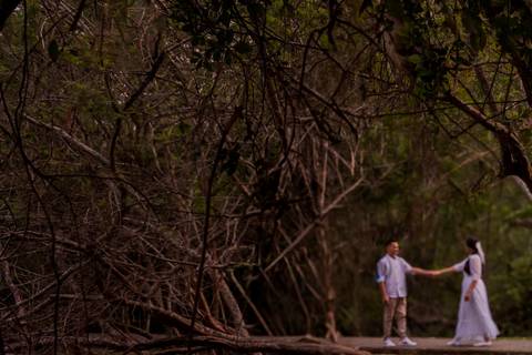 casal caminhando por entre as árvores num parque ecológico durante um ensaio pré-wedding'