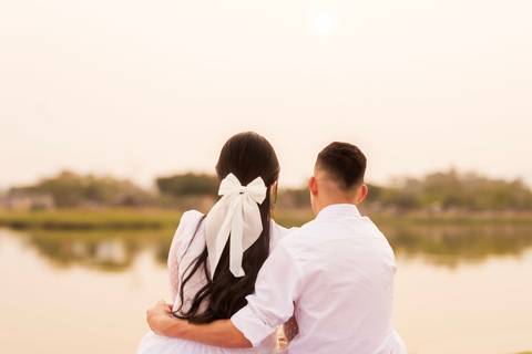 casal abraçados e sentados observando um lago'