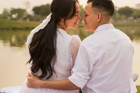 casal em foto romântica sentados próximos a um lago'