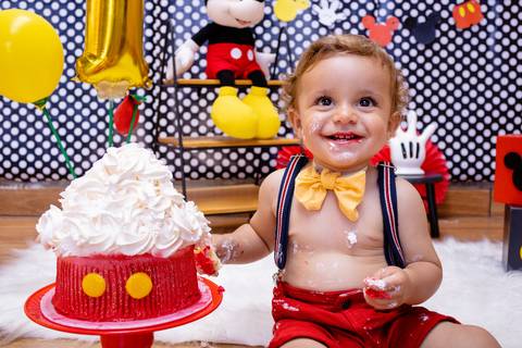 Foto do bebê brincando com o bolo do Smash the cake com decoração de Mickey mouse e com as fotos feitas por Mary Santtiago'