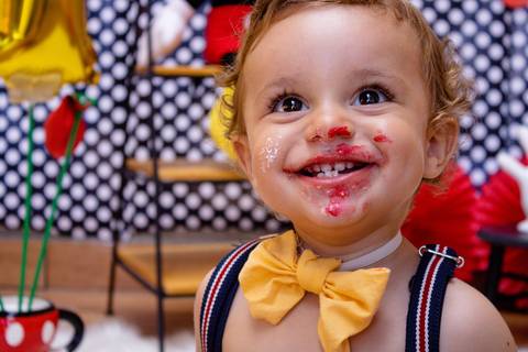 O bebê sorri com a cara cheia de bolo, pois já fez a bagunça no Ensaio Smash the Cake, feito em casa na cidade de Suzano SP, pela fotógrafa Mary Santtiago'