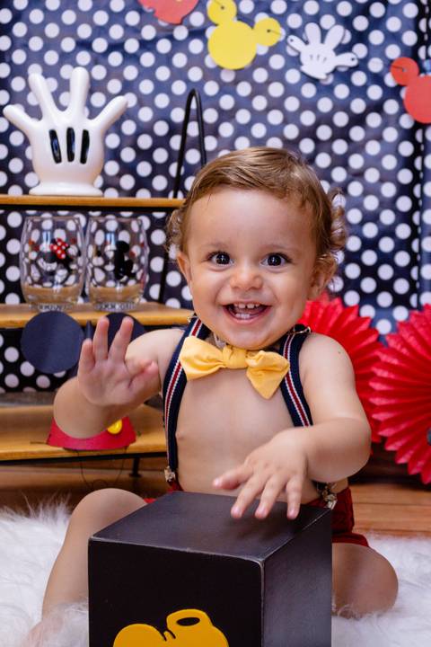 Fotografia do Bebê sorrindo e dando tchau no ensaio do Smash the Cake para comemorar 01 aninho'