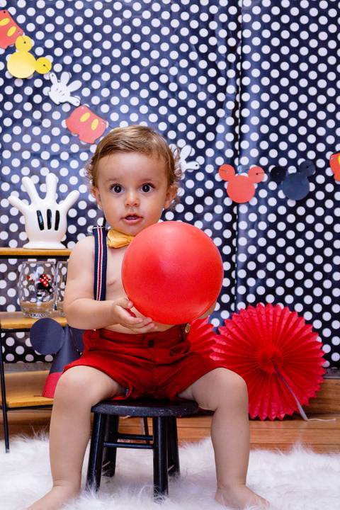 Fotografia do Murilo segurando a bexiga que faz parte da decoração do Smash the Cake com cara de pensativo'