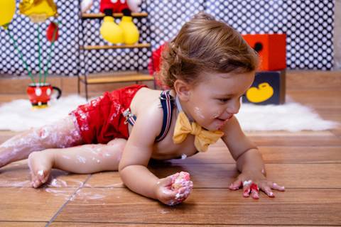 O bebê deita no chão após fazer uma bagunça no seu Smash the Cake em Suzano SP'