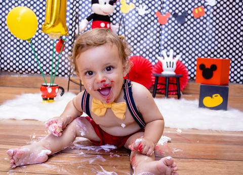 O bebê sorri para a foto com a cara cheia de cobertura do Ensaio Smash the cake feito em Suzano SP pela fotógrafa de Pessoas Mary Santtiago'