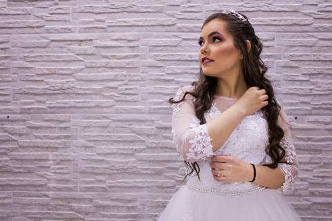 Noiva posando para a foto com o vestido, olhando para a lateral em uma parede neutra. Fotos feitas por Mary Santtiago em Suzano SP'