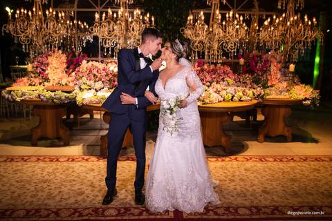 noivos beijando em frente à mesa do bolo'