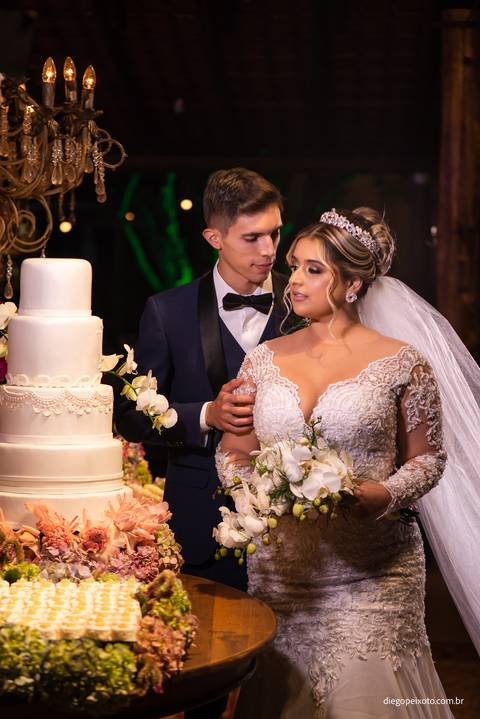 noivos ao lado do bolo de casamento'