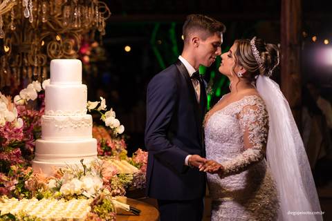 noivos dançam ao lado do bolo de casamento'