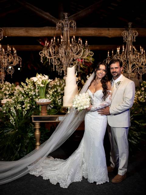 Noivos na mesa do bolo posando para uma foto tradicional de casamento'