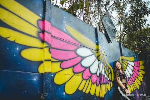 fotografia de uma menina de 15 anos em um grafite de asa no meio da rua'