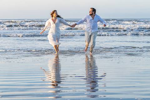 Bruna e Antonio caminhando pela areia de Iguape, em uma cena leve e natural que transmite sintonia e tranquilidade.'