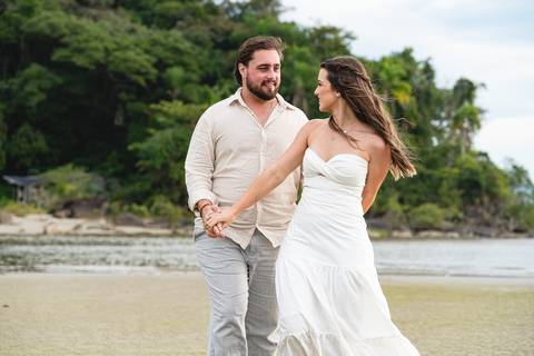 Bruna e Antonio caminhando pela areia de Iguape, em uma cena leve e natural que transmite sintonia e tranquilidade.'