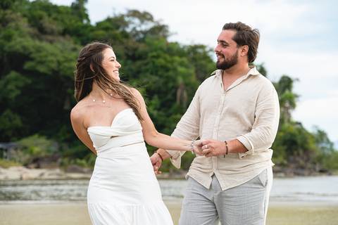 Bruna e Antonio caminhando pela areia de Iguape, em uma cena leve e natural que transmite sintonia e tranquilidade.'
