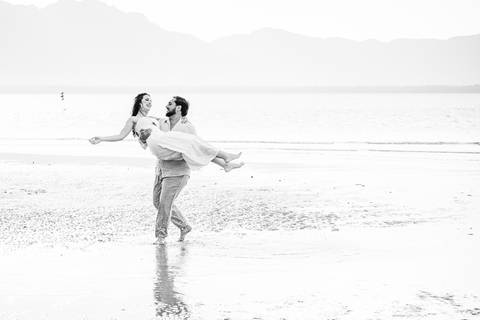 Bruna e Antonio caminhando pela areia de Iguape, em uma cena leve e natural que transmite sintonia e tranquilidade.'