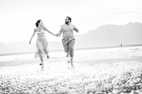 Bruna e Antonio caminhando pela areia de Iguape, em uma cena leve e natural que transmite sintonia e tranquilidade.'