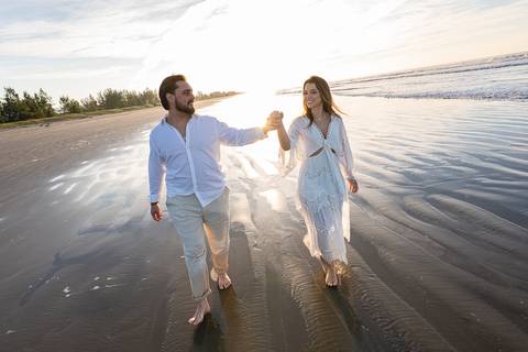 Bruna e Antonio caminhando pela areia de Iguape, em uma cena leve e natural que transmite sintonia e tranquilidade.'