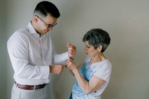 Momento íntimo entre o noivo e a mãe durante os preparativos do casamento. A mãe ajusta os botões de punho com carinho, simbolizando amor e cuidado familiar. Um registo simples e emotivo que destaca a cumplicidade antes da cerimónia.'