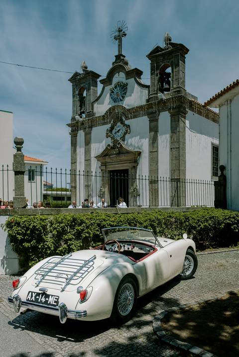 Igreja histórica em Portugal com um elegante carro clássico descapotável estacionado em frente, ideal para casamentos. Este cenário combina tradição e sofisticação, perfeito para fotografias memoráveis. casamento em Portugal, carro clássico, igreja histór'