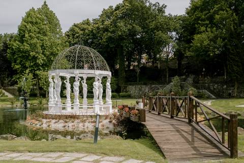 Jardim da Quinta dos Jasminse com estrutura clássica de colunas e cúpula, rodeada por um lago e uma ponte de madeira. Ideal para casamentos e eventos românticos. ardins para casamentos, cenário romântico, eventos ao ar livre, quinta dos Jasmins'