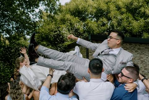 Cena animada de casamento com noivos a serem erguidos pelos convidados, num momento de diversão e união. Festa cheia de alegria, amizade e celebração do amor. noivos, casamento divertido, momentos inesquecíveis, celebração, felicidade.'