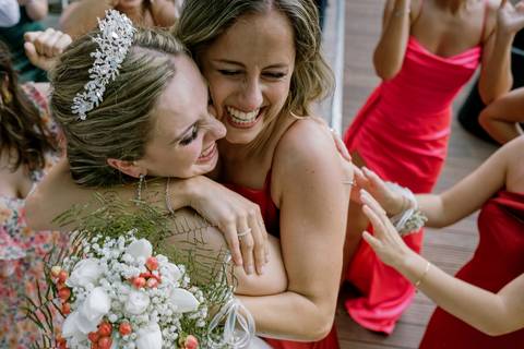 Momento emocionante de celebração entre a noiva e uma convidada após o lançamento do ramo. Expressão de felicidade, conexão e alegria num casamento único.casamento, noiva, ramo de flores, momentos especiais, emoção, celebração, amizade.'