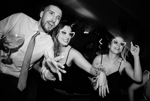 Convidados animados numa festa de casamento, captados a sorrir e a celebrar com óculos divertidos e bebidas na mão. Um momento descontraído que destaca a alegria e a diversão. casamento, festa animada, convidados felizes, celebração, fotografia criativa.'