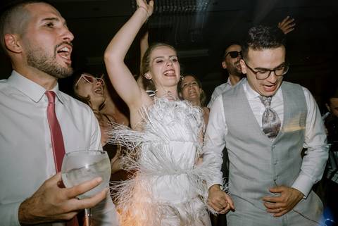 Noiva animada a celebrar na pista de dança, rodeada de convidados felizes, incluindo o noivo e amigos. Um momento de pura alegria durante a festa de casamento. casamento, pista de dança, celebração, noiva feliz, convidados animados, festa inesquecível.'