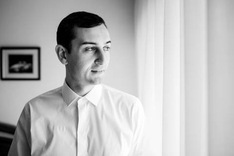 Retrato de noivo em preparação para o casamento, captado em preto e branco. A imagem transmite sofisticação e serenidade. noivo, preparação do noivo, fotografia de casamento, retrato de noivo, casamento.'