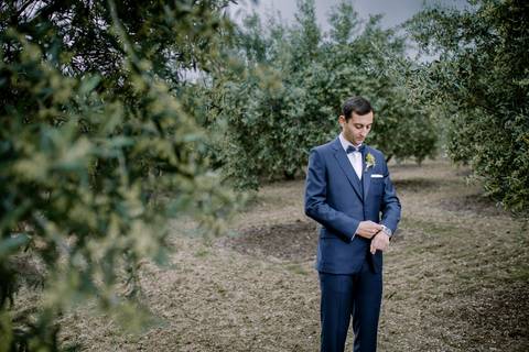 Noivo elegantemente vestido em fato azul ajustando o relógio, captado num cenário natural de oliveiras. Fotografia de casamento em Portugal com um toque clássico e sereno. Noivo
Fotografia de casamento
Casamento em Portugal'