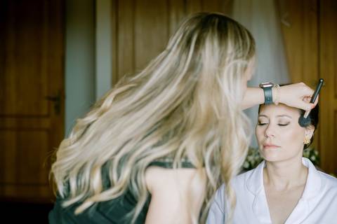 Noiva em preparação no dia do casamento, a ser maquilhada com delicadeza. Captura autêntica e natural de momentos antes da cerimónia, registada por fotógrafo profissional em Oliveira de Azeméis.  preparação da noiva, maquilhagem elegante'