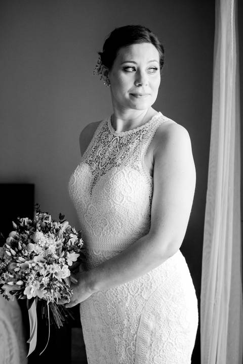 Retrato da noiva no dia do casamento, com vestido de renda elegante e bouquet de flores silvestres. Fundo com tonalidade suave destaca a beleza e serenidade da noiva. casamento, vestido de noiva, bouquet, flores, retrato de casamento.'
