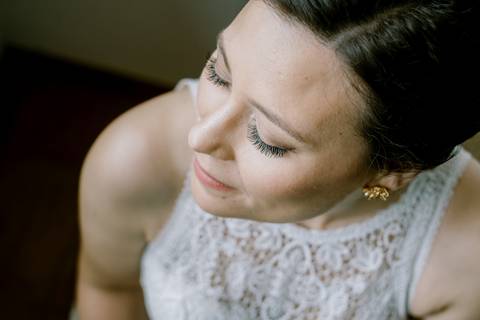 Retrato da noiva capturado de um ângulo superior, destacando a maquilhagem elegante, os cílios perfeitos e os detalhes do vestido de renda. Uma fotografia delicada e intimista que revela a beleza e serenidade do momento. maquilhagem de casamento
'