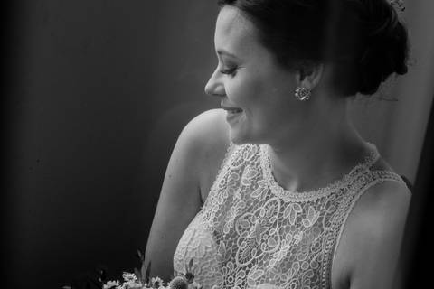 Noiva sorridente captada em preto e branco, destacando o vestido de renda elegante e o bouquet floral. Esta fotografia realça a beleza natural da noiva no dia do casamento.noiva, vestido de noiva, casamento, fotografia de casamento, bouquet de noiva.'