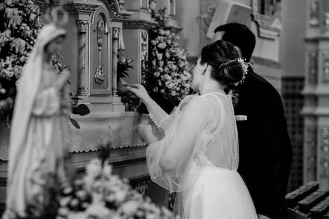 Fotografia de casamento religioso, noivos em momento simbólico diante de altar, numa igreja católica em Portugal. Noiva com vestido elegante e decoração floral destacam a cerimónia. casamento, religioso, altar, noivos, igreja, tradição, Portugal.'