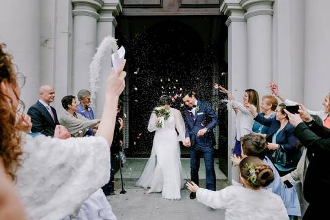 Saída dos noivos da igreja sob uma chuva de arroz e pétalas, rodeados por convidados felizes. Este momento especial captura a alegria do casamento. casamento, saída da igreja, , arroz, pétalas, celebração, fotografia profissional.'