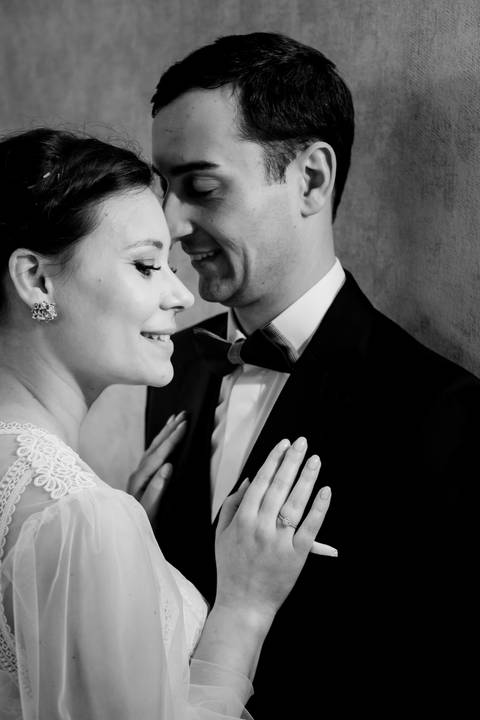 Fotografia de noivos apaixonados em close-up, captada a preto e branco. Noiva com vestido de noiva rendado e anel de noivado em destaque, ao lado do noivo elegante. Perfeito para casamentos, momentos românticos e inspiração para celebrações únicas.'