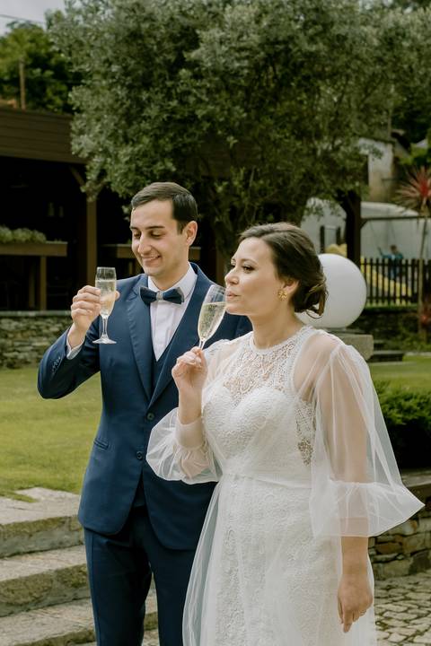 Momento de celebração ao ar livre com os noivos a brindar num cenário elegante rodeado pela natureza. Fotografia captada num ambiente descontraído. fotógrafo de casamento, momentos únicos, celebração ao ar livre.'