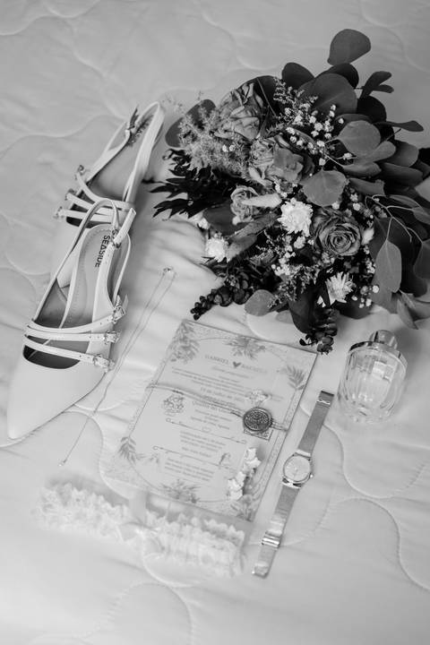 Detalhes da noiva a preto e branco: sapatos, ramo, convite da Quinta do Outeiro, relógio e perfume. Rui Costa Freire Photography capta os pormenores do casamento com elegância e estilo documental em Portugal. Inspirador. detalhes casamento fotografia'