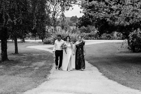 A passagem solene pelos caminhos da Quinta do Outeiro. Em perspetiva de plano geral a preto e branco, Rui Costa Freire Photography imortaliza a cumplicidade familiar no percurso exterior de um casamento luxuoso. Fotografia documental'