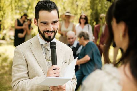 Noivo lê os votos emocionado numa cerimónia civil ao ar livre, rodeado pelos convidados. Fotografia documental de casamento por Rui Costa Freire Photography, com foco em momentos autênticos, elegância e emoção em Portugal. fotografia de casamento'