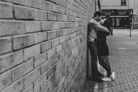 Casal apaixonado encostado a uma parede de tijolos, capturado em preto e branco. Momento romântico, ideal para portfólios de fotografia de casamento. otografia de casamento, casal apaixonado, fotografia preto e branco, fotógrafo de casamentos, sessão'