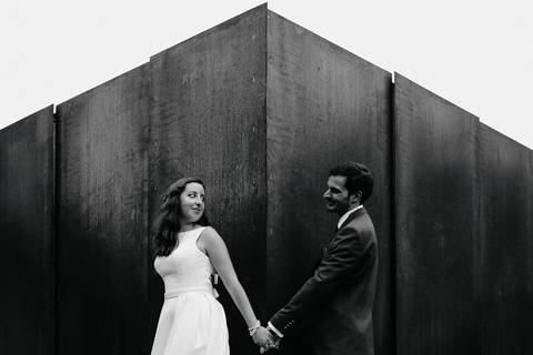 Fotografia de casamento artística em preto e branco, capturando um casal de mãos dadas em frente a uma parede de metal. Ideal para portfólio de fotógrafo de casamentos de rui costa freire Photography de Cantanhede faz sessão de noivos'