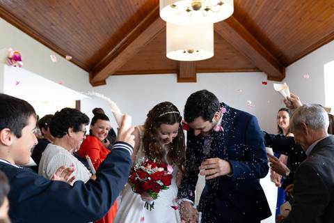 Casal de noivos a sair da cerimónia, rodeados por convidados a lançar arroz e pétalas. A noiva segura um bouquet. portfólios de fotografia de casamento, rui costa freire Photography na quinta das janelas, fotógrafo de Cantanhede '
